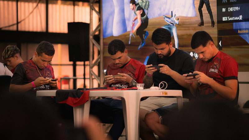 Dynamic collage of popular multiplayer mobile games — Clash Royale, PUBG Mobile, and Among Us — with players celebrating on smartphones and tablets